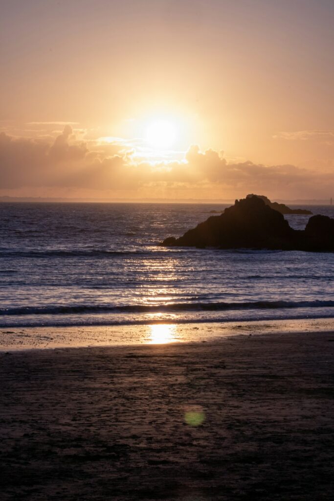 the sun is setting over the ocean on the beach