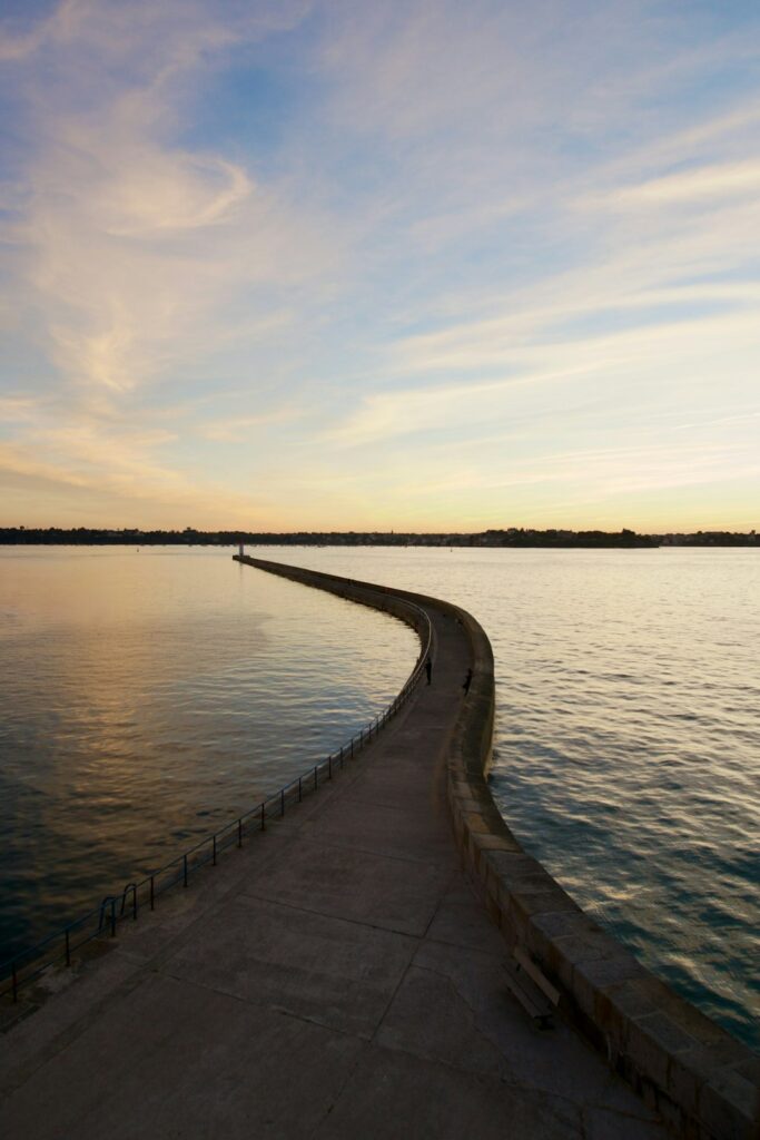 A pier stretches into calming water at sunset.