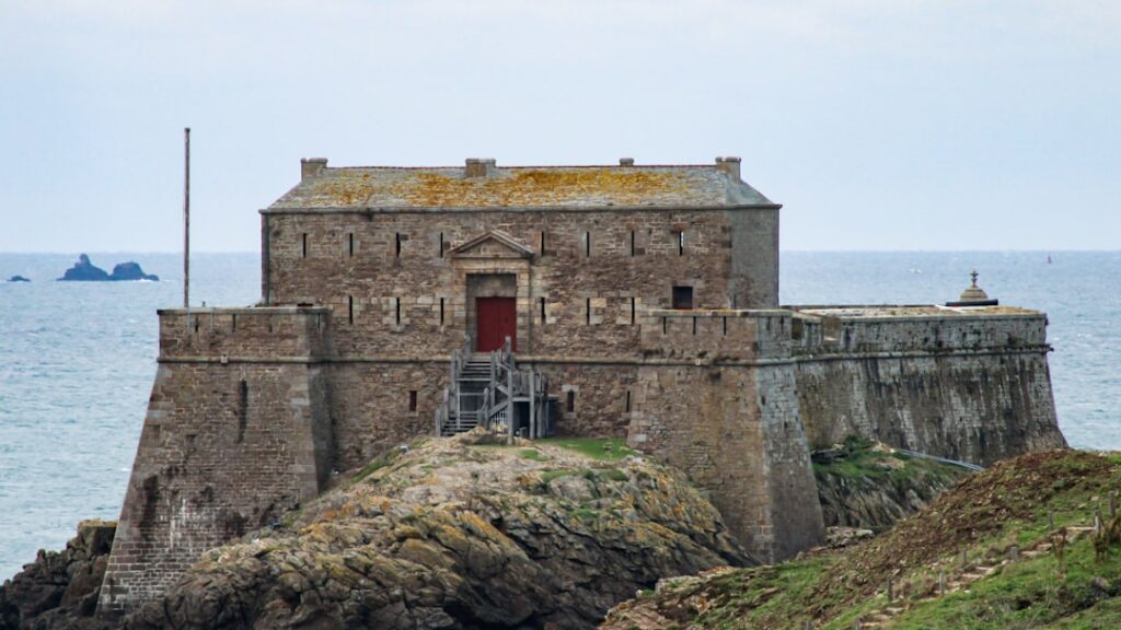 a stone building sitting on top of a cliff next to the ocean
