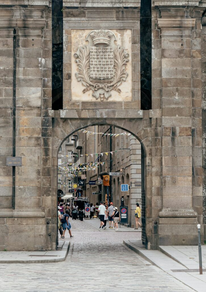 A stone archway leads to a busy street.